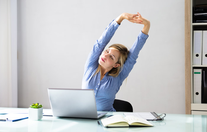 young businesswoman doing stretches while sitting at office desk