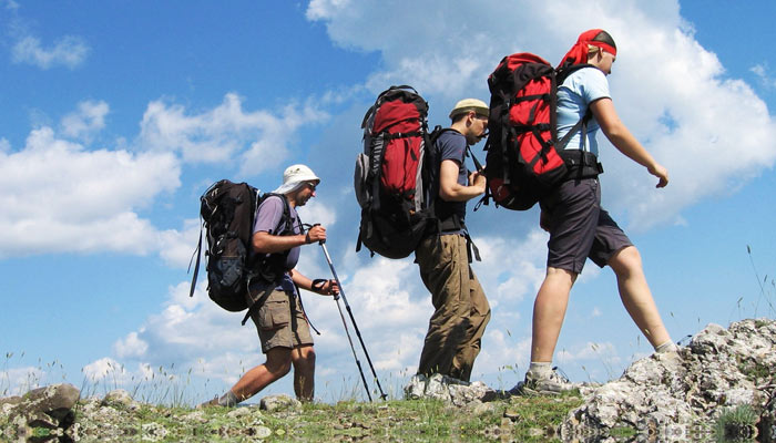 three backpackers hiking mountain