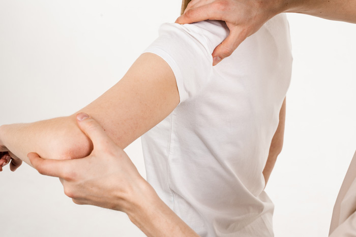 physical therapist gently moving shoulder in assessment